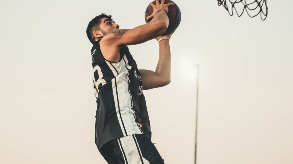 A person is holding up a basketball in front of a fence