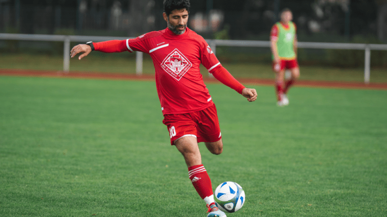 a person in a red uniform is kicking a soccer ball