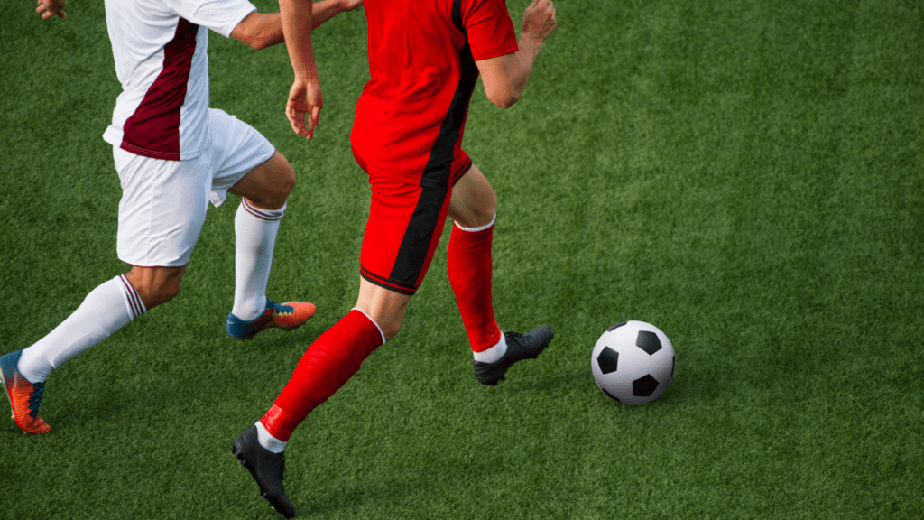 Two people are playing soccer on a field 