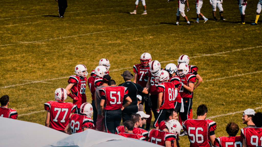 a group of football players huddle together on the field