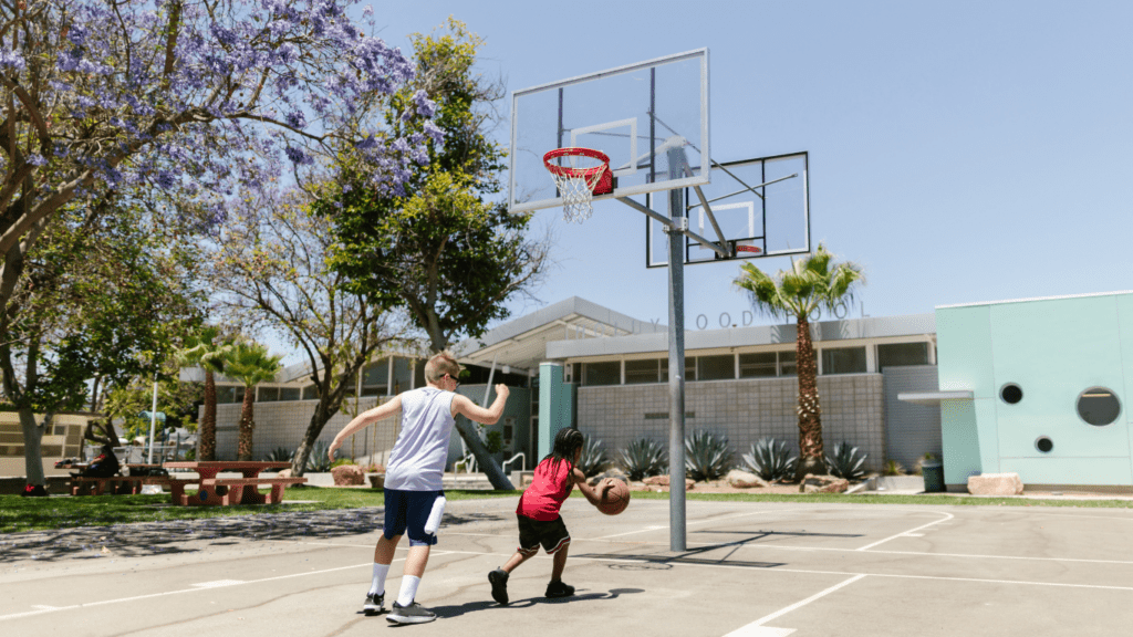 a group of people playing basketball on an outdoor court