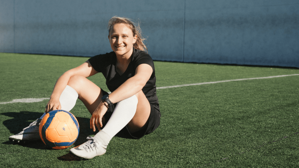 a soccer player sitting on the ground with their hands on their knees