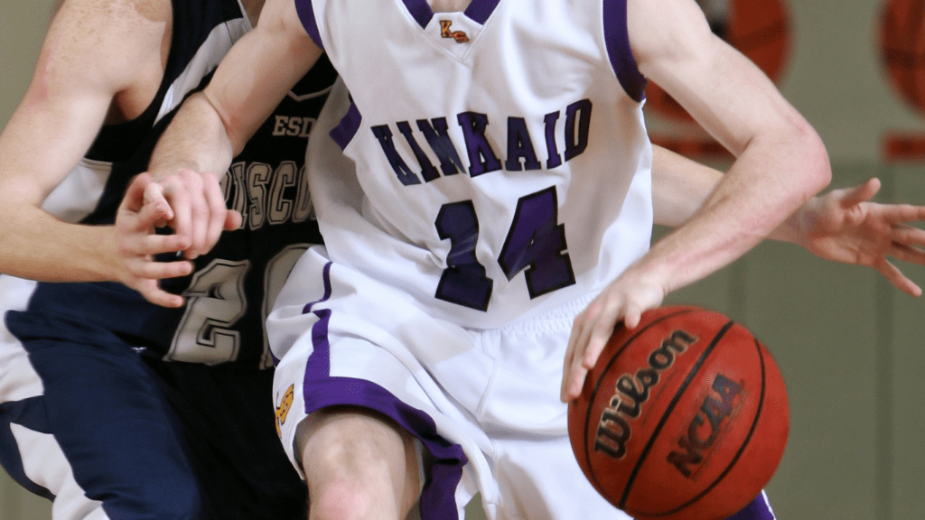 two individuals in purple and white uniforms playing basketball